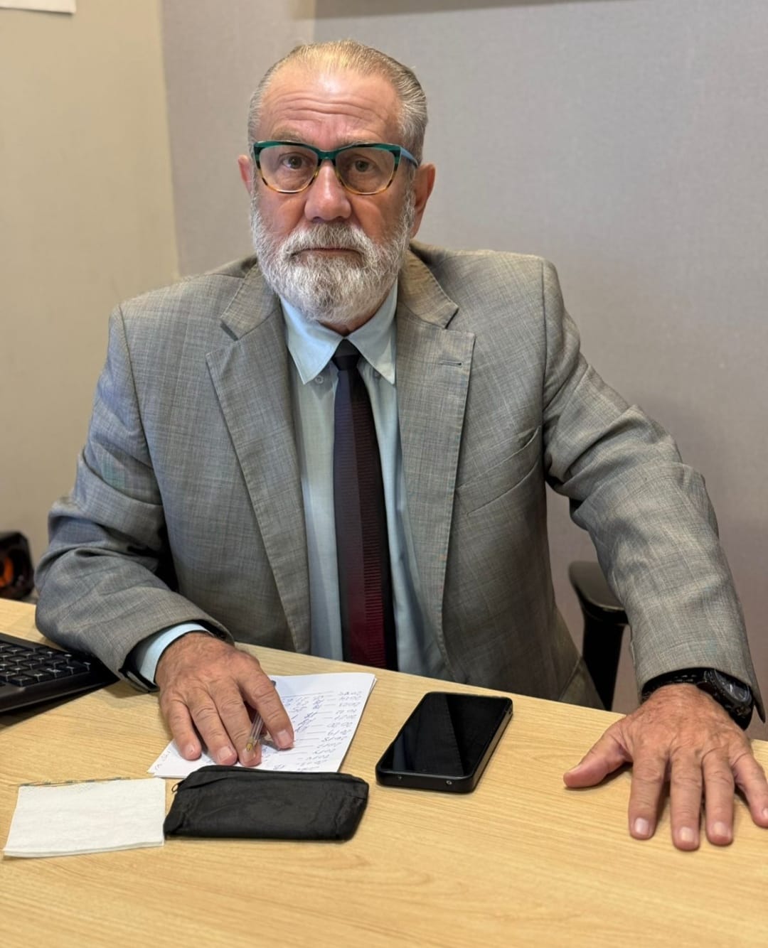 Dr. Aguiberto Camilo Redi sentado à mesa de trabalho, de terno